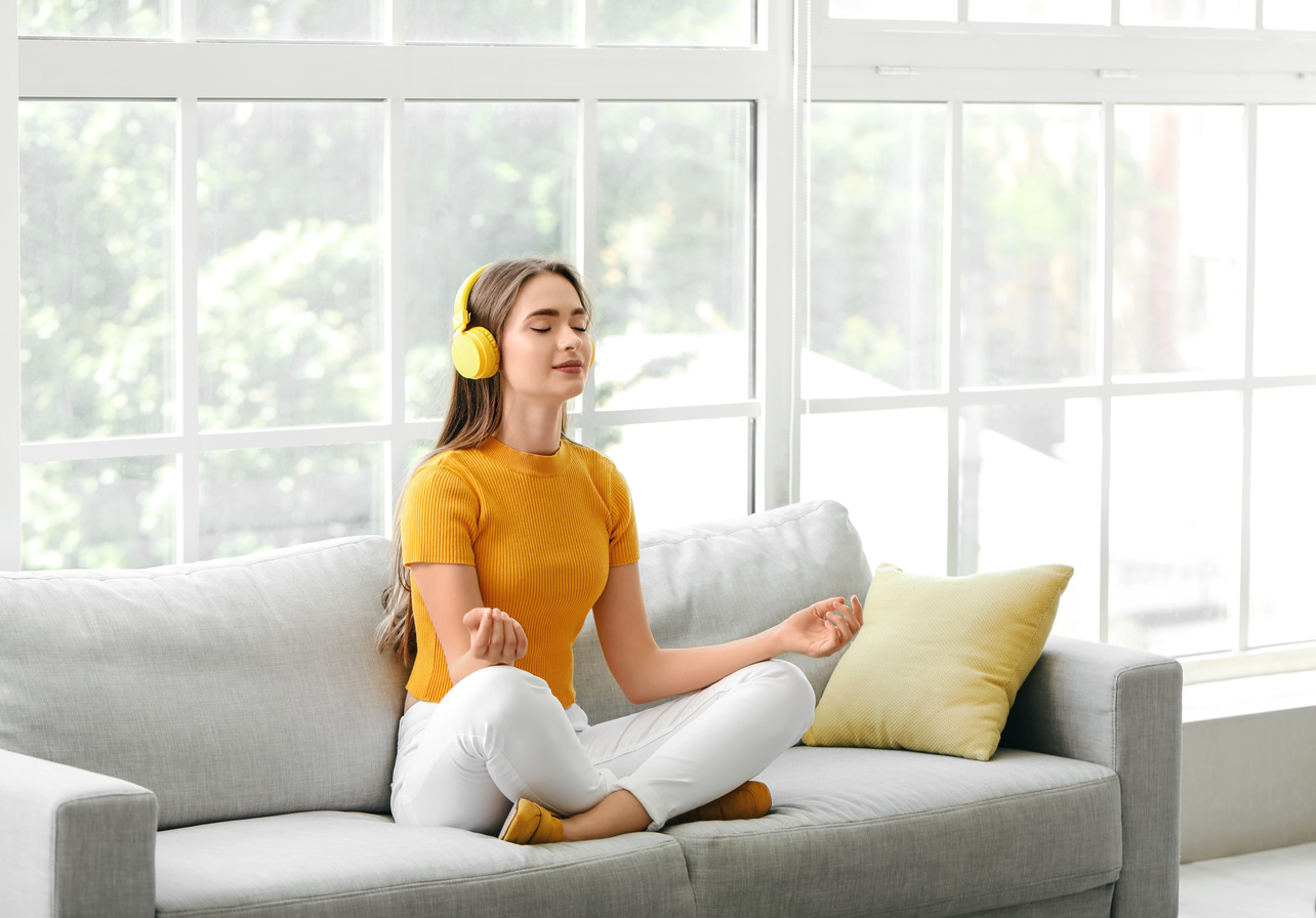 Young Woman Listening to Music While Meditating at Home