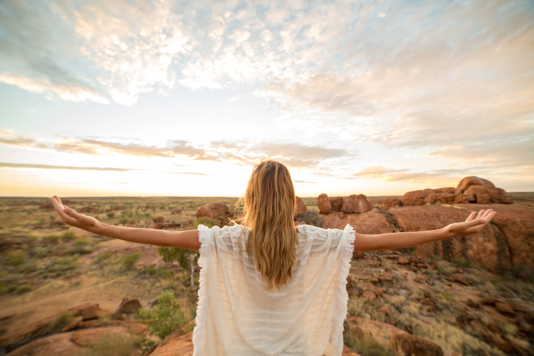 Serene woman arms outstretched in nature, sunrise